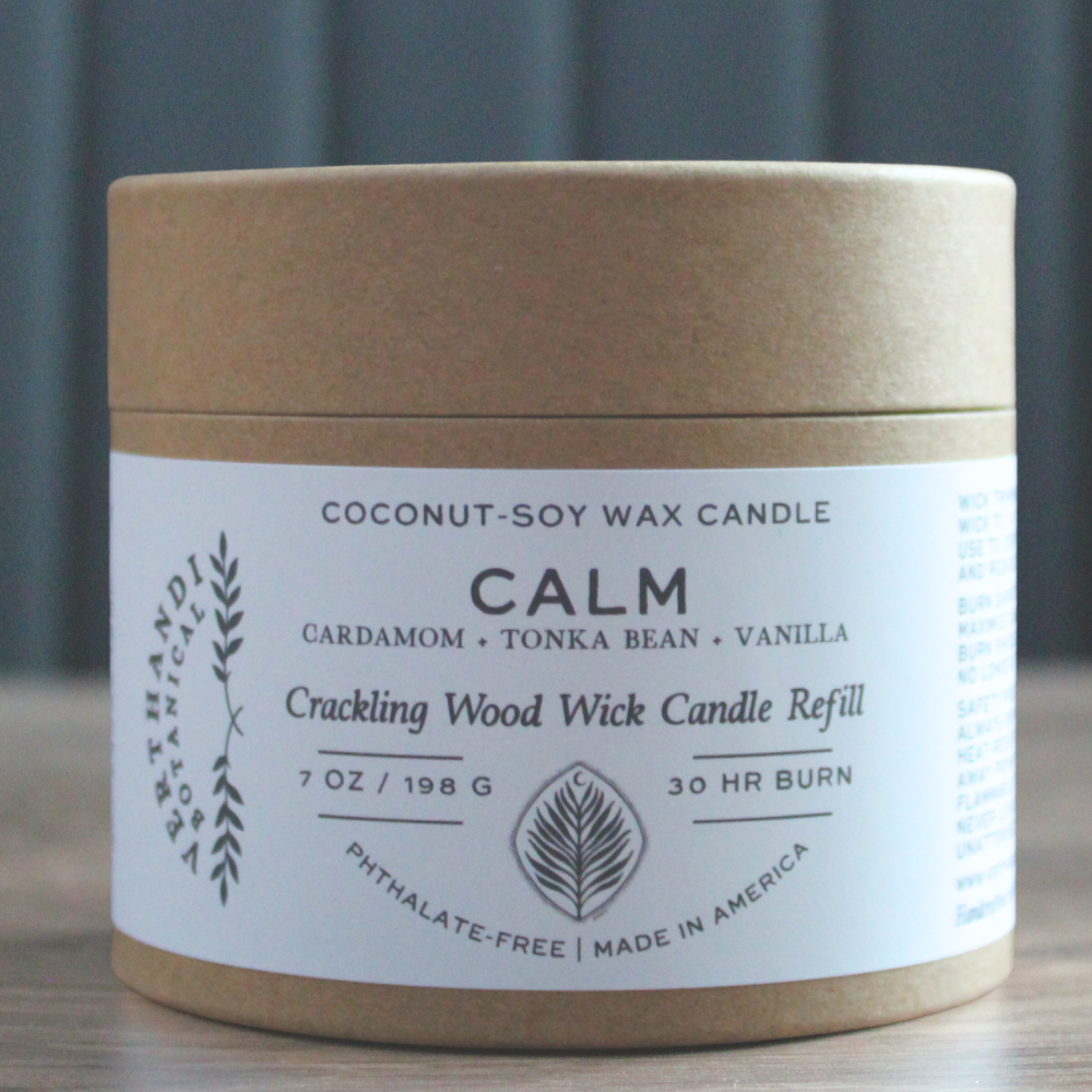 Coconut-soy wax candle refill container with label on a wooden surface