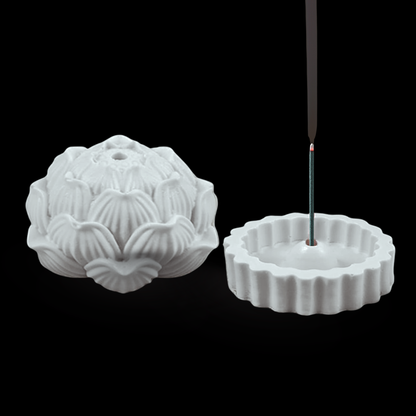 White concrete incense burner shaped like a lotus flower with an incense stick on a black background