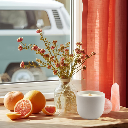 citrus patchouli essential oil candle with coconut soy wax, a crackling wood wick in a concrete jar with a crystal embed, side view on table with a VW bus in the background