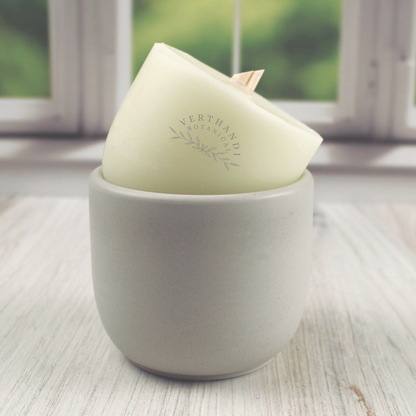 coconut soy wax candle refill with crackling wood wick propped up by an empty concrete candle jar