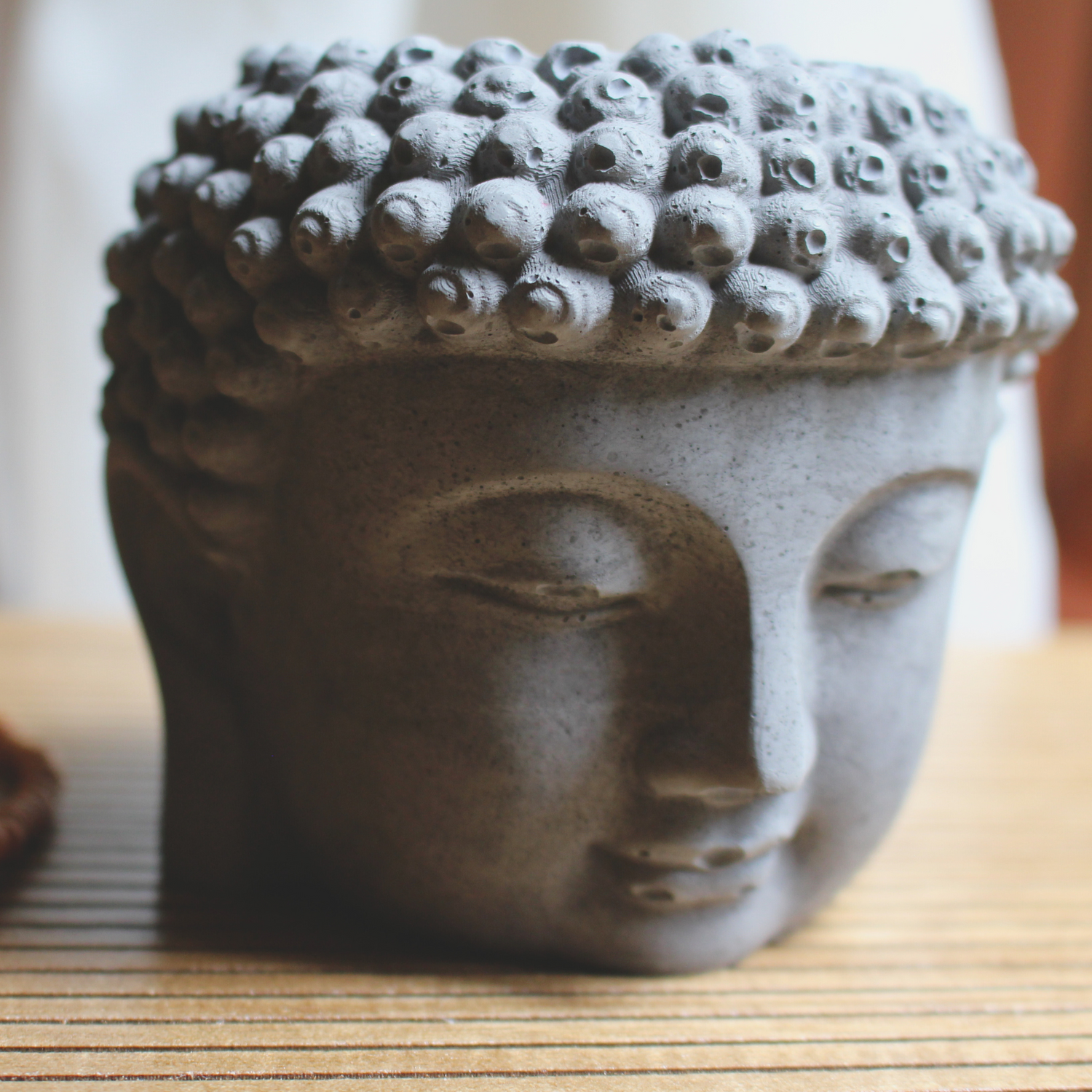 equanimity buddha head coconut soy candle with crackling wood wick in a gray buddha head concrete jar, front view