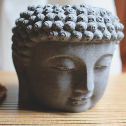 equanimity buddha head coconut soy candle with crackling wood wick in a gray buddha head concrete jar, front view