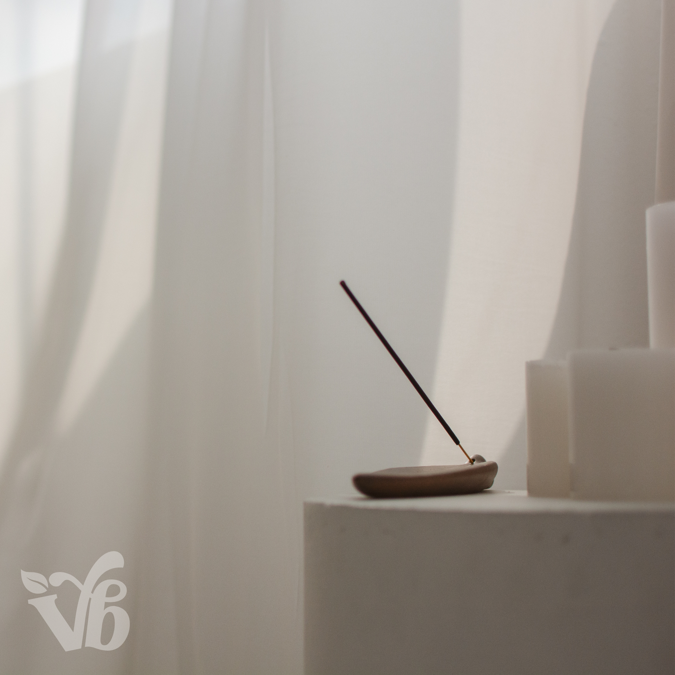 Incense stick on a small dish with white curtains in the background