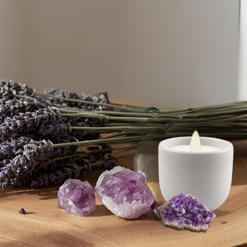 lavender essential oil candle with coconut soy wax, a crackling wood wick, in a concrete jar and a quartz crystal, side view on table